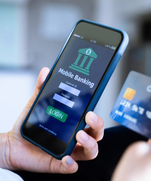 Mobile online banking concept.Close-up of Female hands using mobile phone and holding credit card